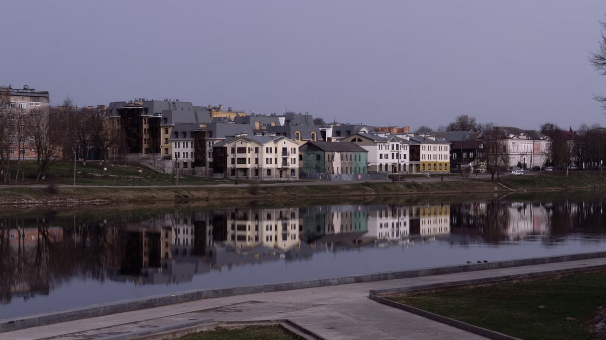 Beautiful riverside homes reflecting in the tranquil water under a soft sky.