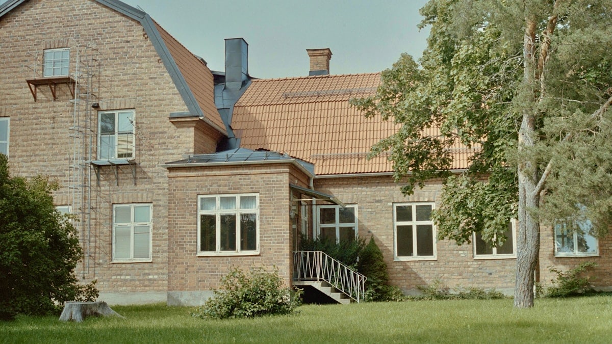 A large brick house sitting on top of a lush green field